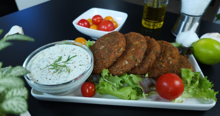 Protein-packed lentil and sweet potato patties served with yogurt dill dip on a white plate